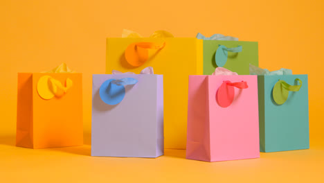 Studio-Shot-Of-Colourful-Birthday-Party-Gift-Bags-Against-Yellow-Background-2